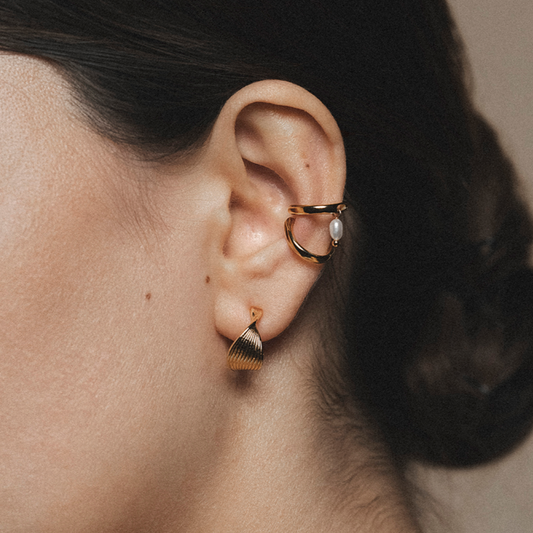 Close-up of a person wearing earrings with a neutral background