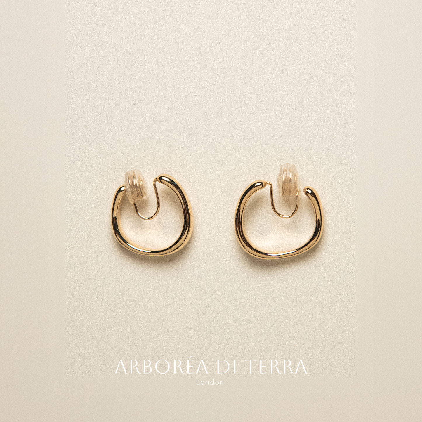 Gold hoop earrings on a beige background with 'Arborea Di Terra' branding.