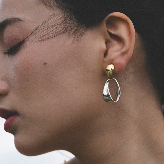 Close-up of a woman wearing gold hoop earrings with a blurred background