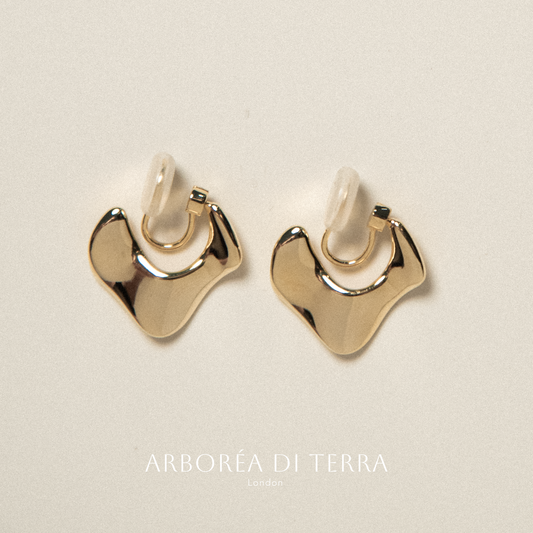 Gold earrings on a beige background with 'Arboréa di Terra' branding.