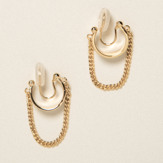 Pair of gold hoop earrings with chains on a beige background