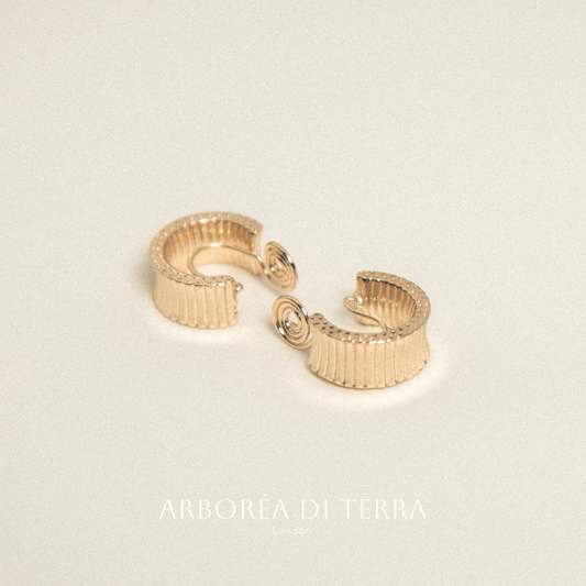 Gold hoop earring on a beige background with 'Arborea Di Terra' branding.