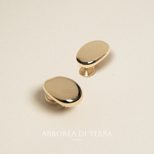 Two gold knobs on a beige background with 'Arborea Di Terra' branding.